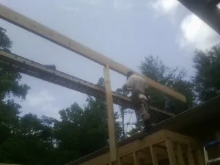 Carpenter setting a ridge beam over a new addition frame — Ice Dam Removal by Roofing Brothers in Galena