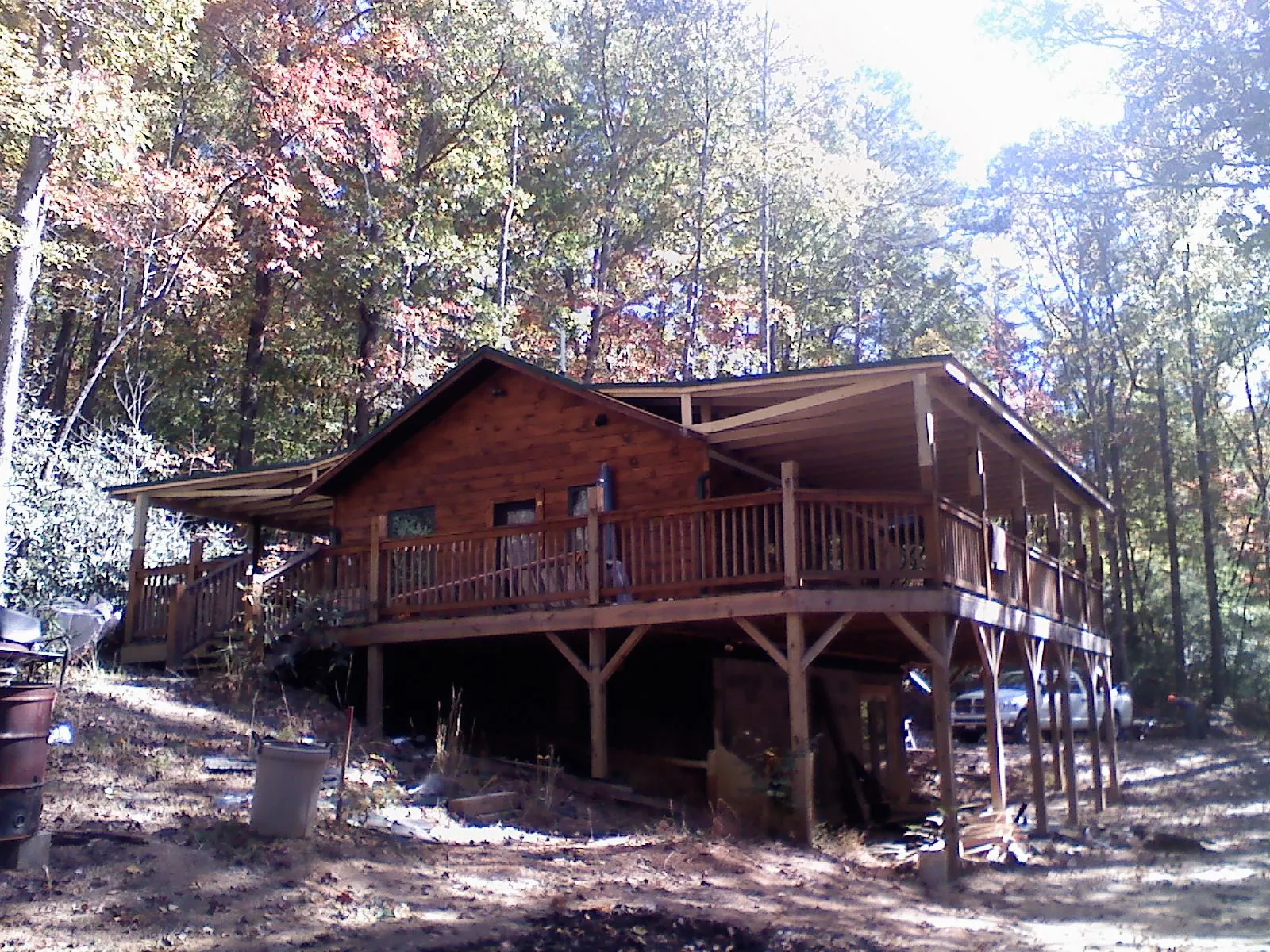 Log cabin with a wraparound porch and metal roof in the fall in Galena